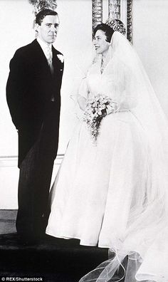 a man and woman standing next to each other in front of a mirror wearing wedding gowns