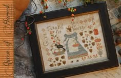 a cross - stitch picture frame with autumn leaves and an image of a woman's dress