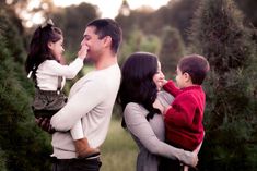 a man and two children are standing in front of some trees with their mouths open