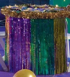 a table topped with a cake covered in purple, green and gold tinsels