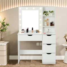 a white vanity with lights on it next to a potted plant and a mirror