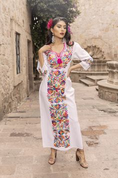 This Beautiful Mexican Floral Dress is the perfect dress for a special event or Mexican Fiesta.  It reflects the Mexican culture through its unique embroidered design and vibrant colors.  It has laces to tie on the back for an adjustable and comfortable fit.  It is embroidered by Artisanal Machine- hand manipulated by Mexican Artisans in Puebla, Mexico. It's made out of fresh Mexican Cotton and is full of embroidered multicolor flowers. Size S - 2X Shop more Mexican Dresses here:  https://www.et Mexican Pink Dress, Elegant Mexican Outfit, White Mexican Dresses For Women, Traditional Mexican Dress For Women, Mexican Attire Women, Wedding Dresses Mexican Style, Mexico Traditional Dress, Mexican Fiesta Party Outfit Women, Mexican Wedding Dress Embroidered