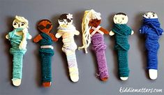 five knitted dolls are lined up on a gray surface, with one doll in the middle