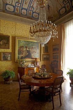 a dining room with a chandelier hanging from the ceiling and paintings on the walls