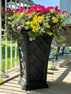 a large black vase filled with flowers on top of a porch