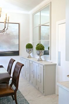 a dining room table with chairs and two vases on it's centerpiece