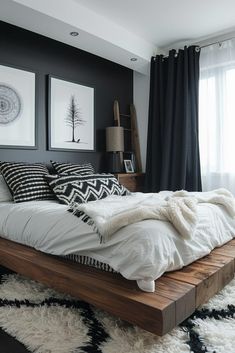 a bedroom with black walls and white bedding is pictured in this image, there are two framed pictures on the wall above the bed