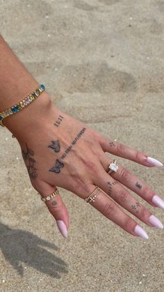 a woman's hand with tattoos on it and two different bracelets around her wrist