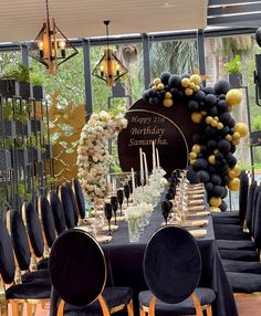 a black and gold birthday party setup with balloons, flowers, and candles on the table