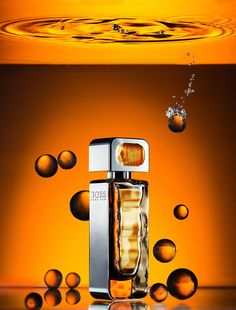 an orange background with bubbles and a bottle of perfume in the foreground that is falling into the water