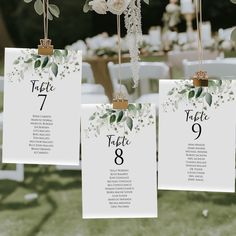 the table numbers are hanging from strings with flowers and leaves on them for an elegant touch