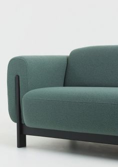 a green couch sitting on top of a white floor next to a wooden frame chair