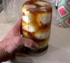 a hand holding a jar filled with liquid