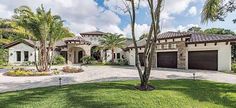 a large house with palm trees in the front yard and landscaping on both sides of it