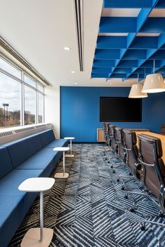 an empty conference room with blue and white walls, long benches, and large windows