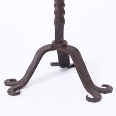 an old fashioned metal table with a wooden top and two twisted legs on the base