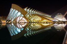 the building is lit up at night and reflecting in the water