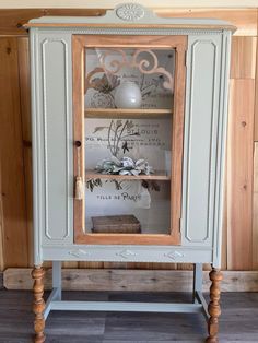 an old china cabinet with glass doors and wooden legs, painted in pale blue paint