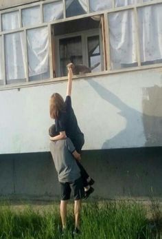 two young boys are reaching up to paint the outside of a house with words above them