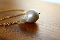 "This genuine Freshwater Baroque Pearl Necklace is absolutely stunning. This large white Pearl has an incredible rich luster. Baroque pearls are pearls with an irregular non-spherical shape. Shapes can range from minor aberrations to distinctly ovoid, curved, pinch, or lumpy shapes. Most cultured freshwater pearls are baroque because freshwater pearls are mantle-tissue nucleated instead of bead nucleated. Pearl measures around 1\" long. Each pearl has a unique natural shape, no two pearls are go White Baroque Pearl Necklace, Extra Long Earrings, Pearl Necklace Gold, Boho Statement Necklace, Baroque Pearl Necklace, Gold Pearl Necklace, Message Jewelry, Pearl Pendant Necklace, Freshwater Cultured Pearls