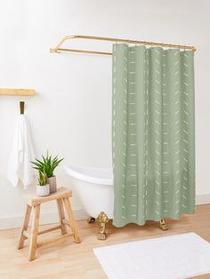 a bathroom with a green shower curtain next to a white bath tub and wooden stool