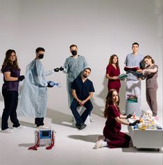 a group of people standing around each other in front of a white background with one person dressed as a doctor