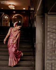 a woman in a pink sari walking down some stairs