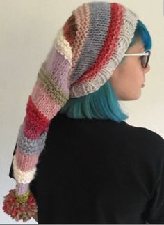 a woman with blue hair wearing a multicolored knitted hat and scarf over her head