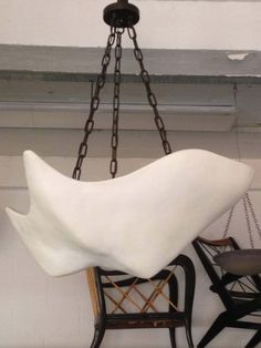 a white sculpture hanging from a ceiling in a room with two chairs and a table