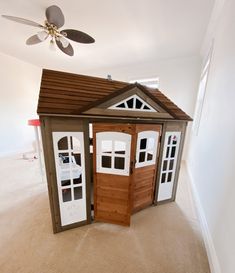 a small wooden house with two doors and a ceiling fan in the middle of it