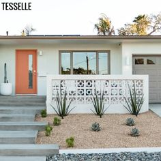 a white house with cactus plants in the front yard and steps leading up to it