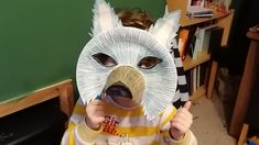 a young boy wearing a paper plate animal mask