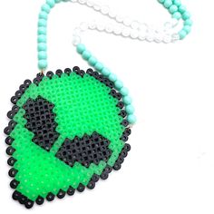 a green and black beaded necklace with an alien face in the center on a white background