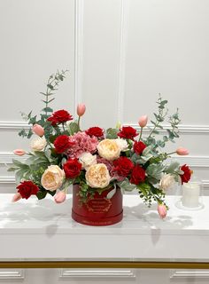 a bouquet of flowers sitting on top of a white table next to a candle holder