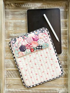 an ipad case sitting on top of a wooden table next to a pen and paper