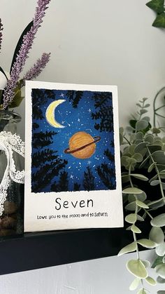 there is a card with an image of saturn and the words seven on it, next to some plants