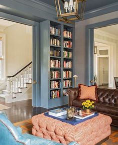 a living room filled with furniture and bookshelves next to a stair case full of books