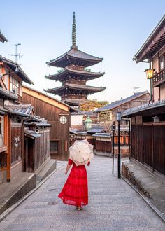 a woman in a red dress walking down a street with an umbrella over her head