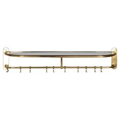 a gold metal shelf with hooks on it