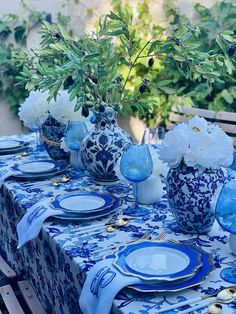 a table set with blue and white plates and vases