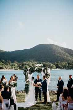 a couple getting married at the end of their wedding ceremony in front of a lake