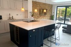 a kitchen with an island and bar stools next to the counter top in front of a brick wall