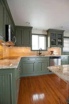 an empty kitchen with green cabinets and wood flooring on the wooden floor is shown