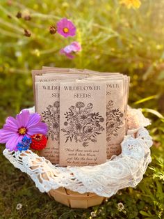 three seed packets sitting on top of a basket in the grass next to some flowers