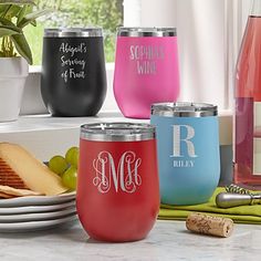 four wine glasses with monogrammed names are sitting on a counter next to plates and utensils