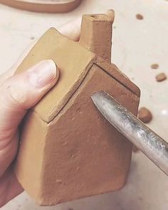 a person is holding a clay house with a knife in it's hand,