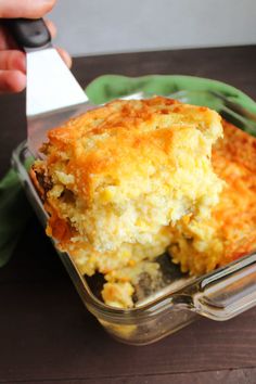 a casserole dish with meat and cheese in it being held by a person