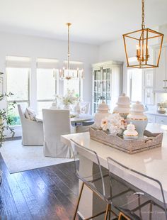 a dining room table and chairs with flowers on the center island in front of them