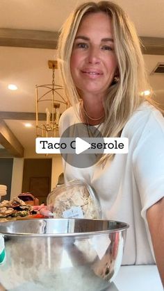 a woman standing in front of a mixing bowl with food on it and the words taco cerrole above her