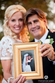 a bride and groom pose for a wedding photo holding up an old fashioned picture frame